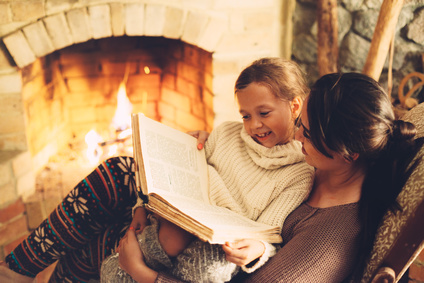 Mutter und Kind vor dem Kamin während sie ein Buch lesen