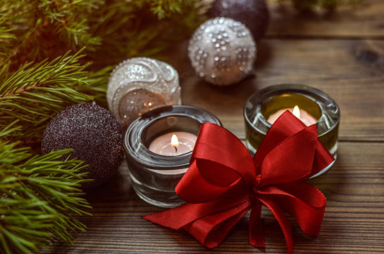 Weihnachtsbild Tannenast Christbaumkugeln zwei angezündete Kerzen eine rot Schleife