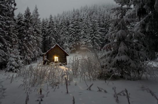 Winterbild schneebedeckter Wald kleine Holzhütte mit Licht