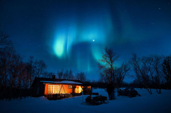 Winterbild bei Nacht Hütte mit Feuerschale und Nordlichter