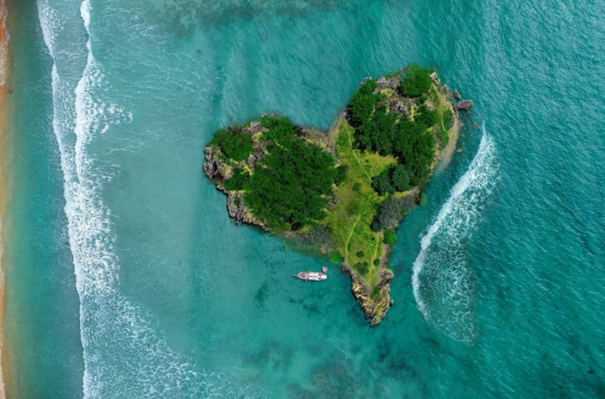 Insel in Herzform und ein Boot auf türkisen Wasser