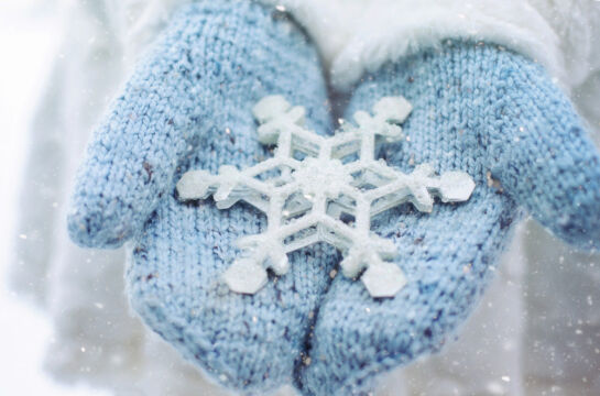 Winterbild blaue Handschuhe halten eine grosse Schneeflocke
